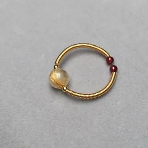 Macro shot of 14K wire wrapped ring with golden rutilated quartz and garnet beads