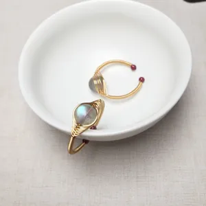 Detail von handgefertigten 14K Golddraht-Ringen mit Labradorit und roten Glasperlen