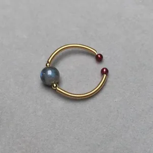 Macro shot of 14K gold-wrapped wire ring with labradorite and red stone accents