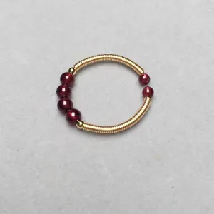 Detailed macro of a 14K gold-wrapped spiral ring featuring dark red garnet beads