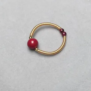Macro shot of 14K gold wire-wrapped ring with vibrant red garnets and cinnabar beads