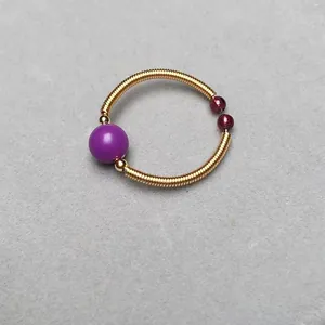Macro shot of gold wire-wrapped ring featuring purple matte bead and dark red garnet accents