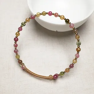 Gros plan d'un bracelet en perles de cristal naturel avec des accents en or 14K sur lin