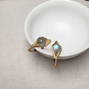 Handgefertigte 14K Golddrahtringe mit Labradorit und Mondstein auf Keramikschale
