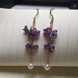 Detail von Hängeohrringen mit violetten Amethyststeinen und eleganten weißen Perlen