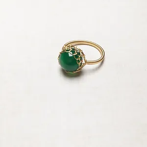 Makroaufnahme von handgewickeltem 14K Golddraht um einen grünen Achatstein an einem Ring