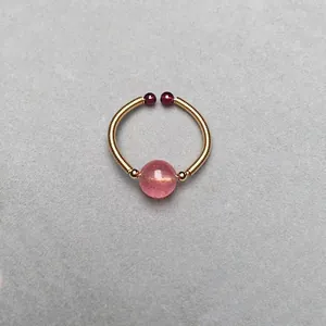 Macro detail of 14K gold-wrapped spring ring featuring strawberry quartz and garnets