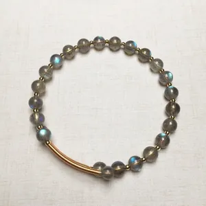 Gros plan sur un bracelet en labradorite avec des perles dorées et éclats bleus