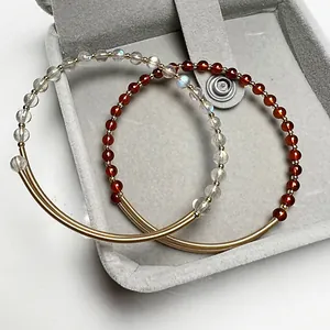Macro detail of 14K gold wire wrapped bracelets with garnet and labradorite beads