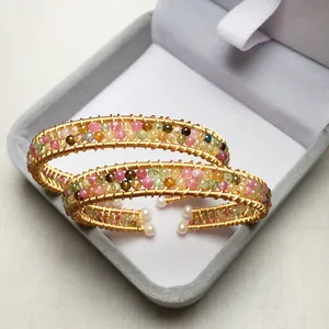 Close-up of 14K gold filled wire wrapped bangles with tourmaline and pearl details