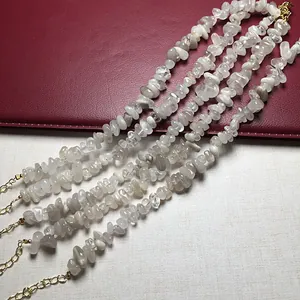 Detail of four strands of irregular white crystal beaded necklaces with gold metal clasps