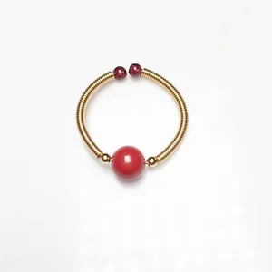 Macro shot of 14K gold wire wrapped ring with central red garnet bead and gold accents