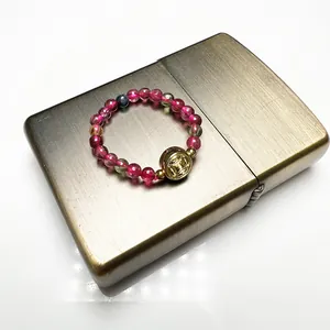 Detailed top view of beaded garnet tourmaline ring with golden coin charm on a lighter
