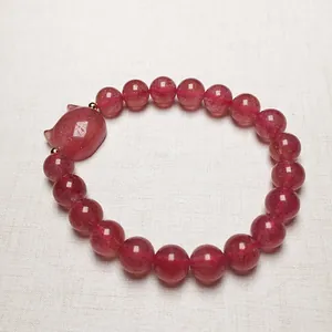 Close-up of strawberry quartz beaded bracelet featuring a cute cat-shaped charm and gold accents