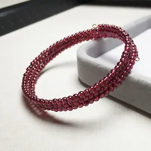 Détail du bracelet multi-rangs en perles de grenat bordeaux avec fermoir doré sur boîte