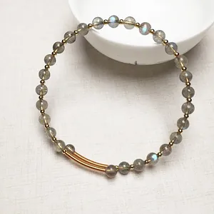 Gros plan d'un bracelet en perles de labradorite avec reflets bleus et détails en or 14K
