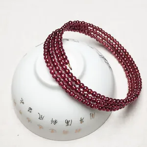 Gros plan d'un bracelet multi-tours en perles de grenat rouge de 2,6 mm sur céramique