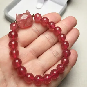 Close-up of strawberry quartz cat bead bracelet with golden spacers on hand