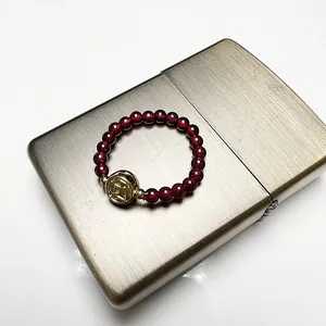 Macro detail of garnet bead ring with a gold coin charm on a metallic surface