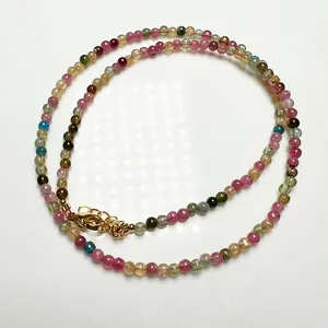 Gros plan d'un collier en perles de tourmaline colorées avec fermoir mousqueton doré