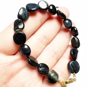 Blue tiger eye beaded bracelet with 14K gold plated clasp shown on hand against white background
