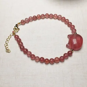 Detailed view of pink strawberry quartz bracelet with a cute pig charm and gold lobster clasp
