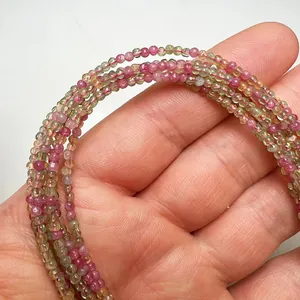 Macro view of ultra-fine 2mm faceted tourmaline candy color beads held in hand