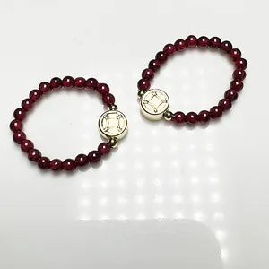 Deep red garnet bead rings with 14K gold plated coin charms on a white background