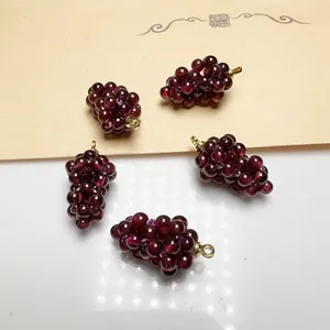 Macro shot of 5 garnet grape pendants with gold loops on an elegant artistic background