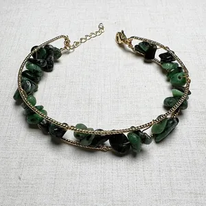 Detail view of handmade gold chain bracelet with green and black raw stone chips