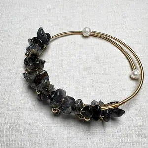 Macro detail of handmade wire-wrapped gold bracelet with natural raw grey gemstones and pearls