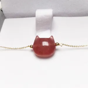 Macro view of strawberry quartz cat-shaped pendant on a delicate gold chain in a jewelry box