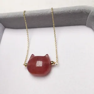 Detailed close-up of a strawberry quartz cat pendant on a fine gold-plated chain