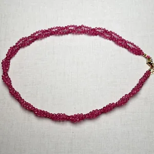 Macro detail of multi-strand braided spinel necklace with faceted rose red beads and gold clasp