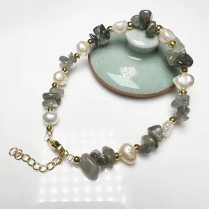 Detailed macro view of baroque pearls and irregular grey gemstones with gold beads and clasp