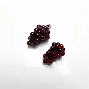 Macro detail of handmade rose red garnet grape pendants with elegant silver clasp hook