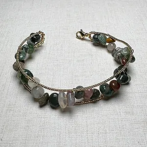 Detail of bohemian multilayer bracelet with colorful natural crystal stone beads and gold chain
