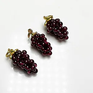 Detailed macro view of three rose red garnet grape pendants with elegant gold metal loops