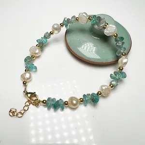 Detailed close-up of baroque pearls with green crystal stones and gold clasp on a bracelet