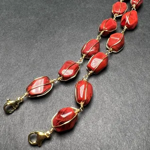 Macro view of red stone beads with 14K gold wire wrapped detailing and lobster clasp