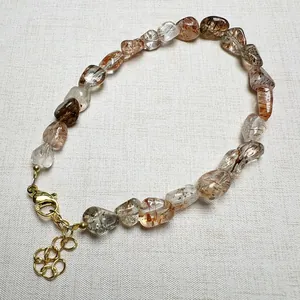 Macro detail of raw red rutilated quartz crystal bracelet with gold lobster clasp