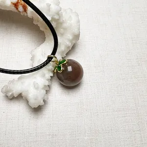 Retro sunstone crystal ball pendant with gold leaf cap on black braided leather cord
