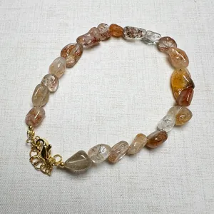 Detail of natural crystal beads with internal fibers and gold-tone lobster clasp
