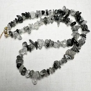 Polished black rutilated quartz chip necklace with gold lobster clasp on white fabric