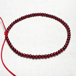 Macro shot of 4mm garnet beads with cat-eye effect on adjustable red cord