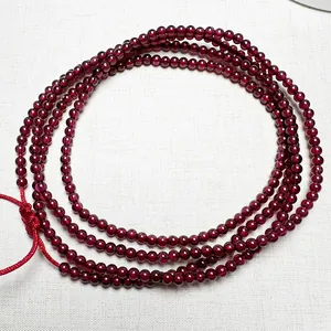 Macro shot of multi-layer garnet bead bracelet with red woven cord on white fabric