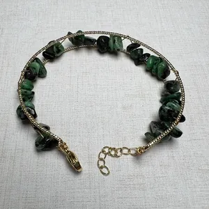 Detail view of handmade gold twisted bracelet with natural green and black raw stone chips
