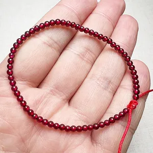 Adjustable garnet beaded bracelet with red cord for women shown on a palm
