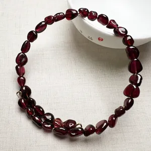Détail d'un bracelet en perles de grenat rouge foncé sur un bol en céramique blanc