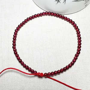 Adjustable garnet red string bracelet and necklace set for women on white fabric